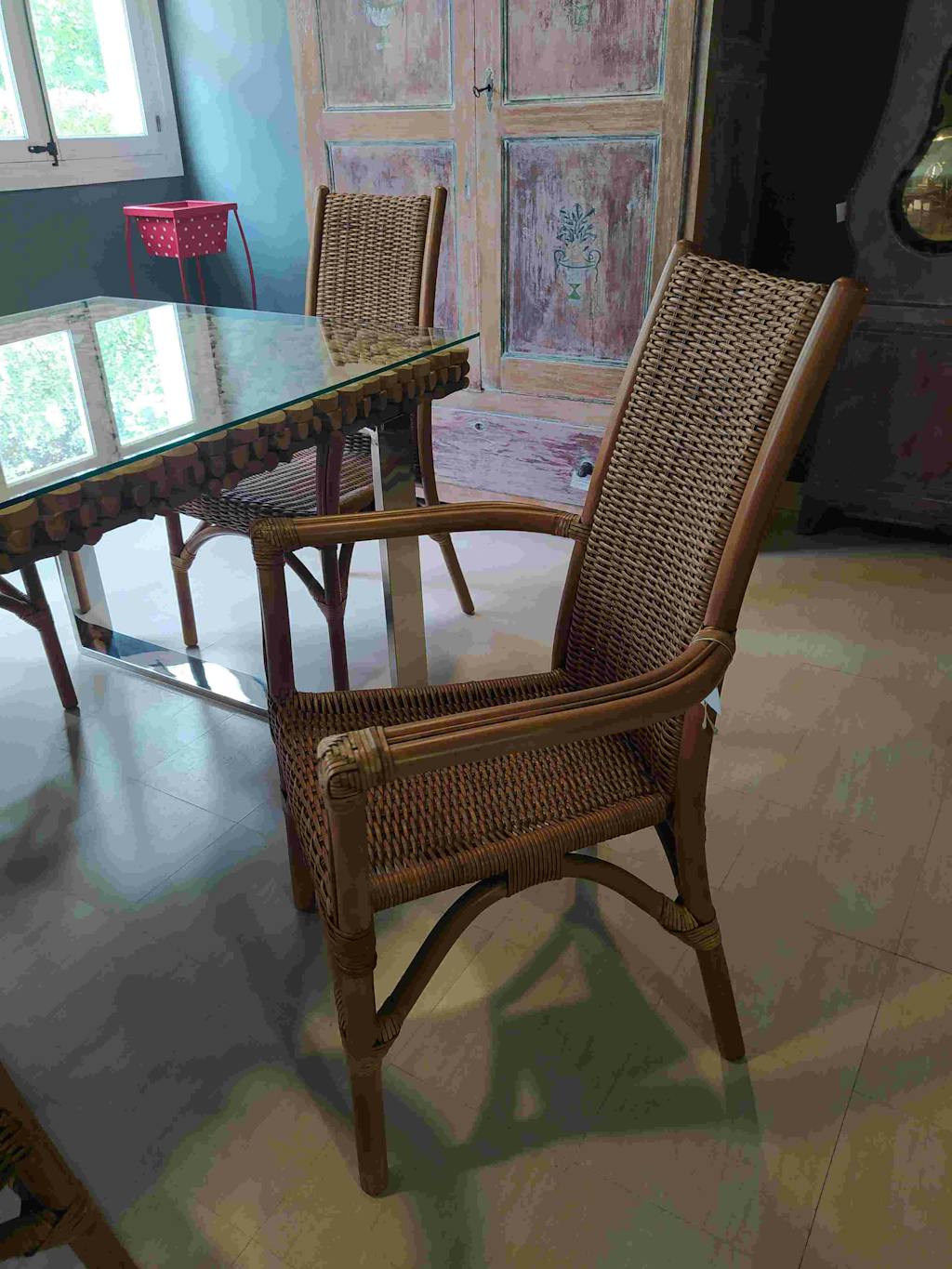 Brown cane chair with armrests.